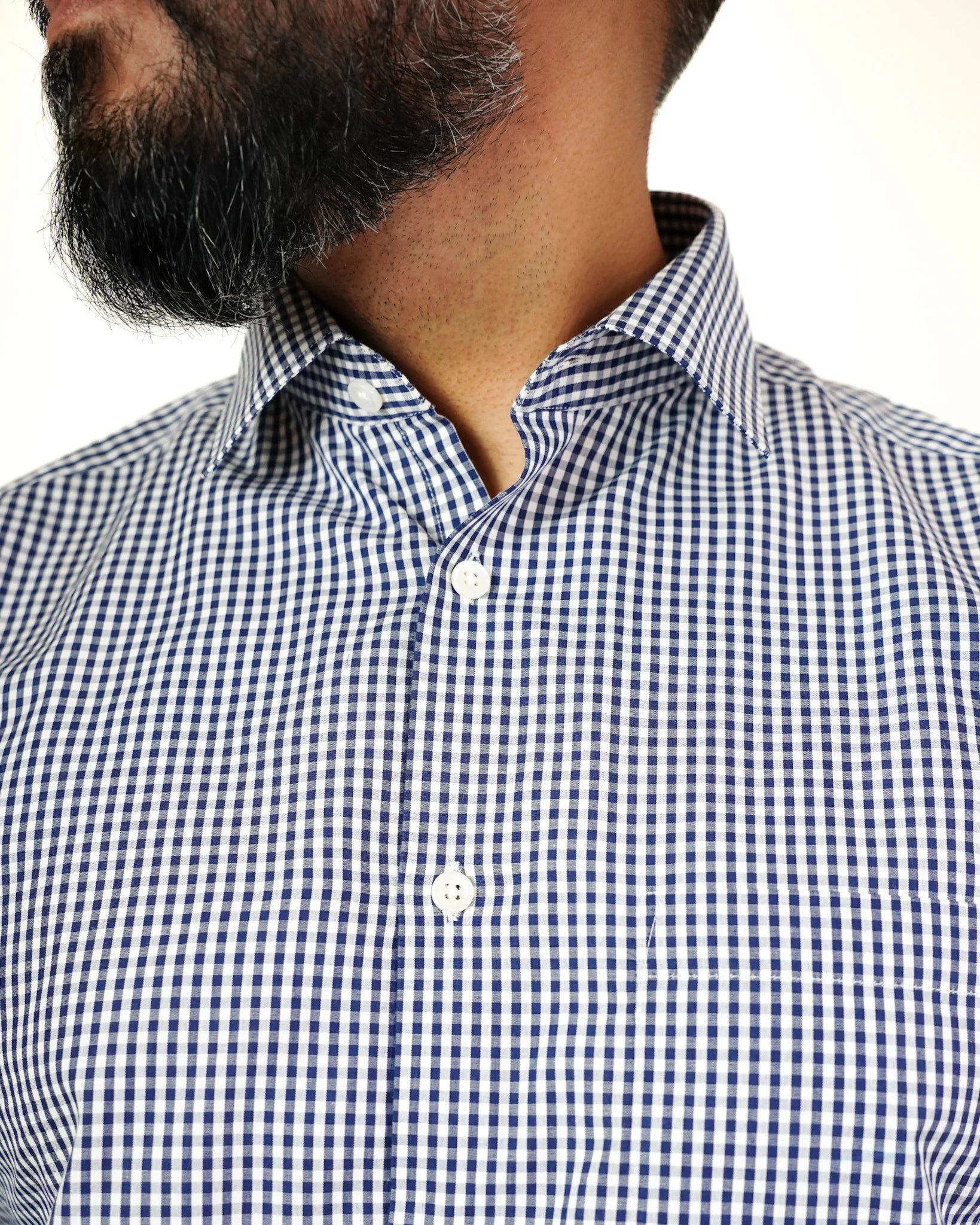 A close-up of a man in a blue and white checked shirt, showcasing the fabric pattern and his facial features.