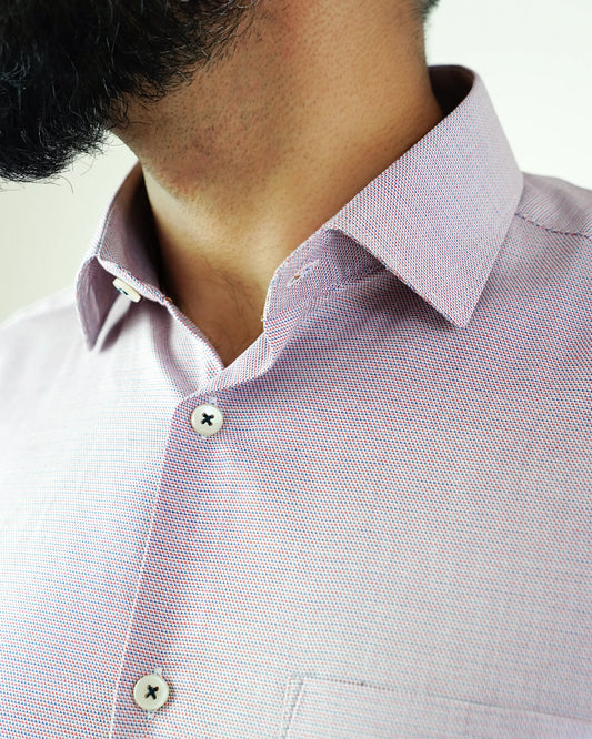Close-up of a person in a red and navy textured shirt with collar buttoned up.