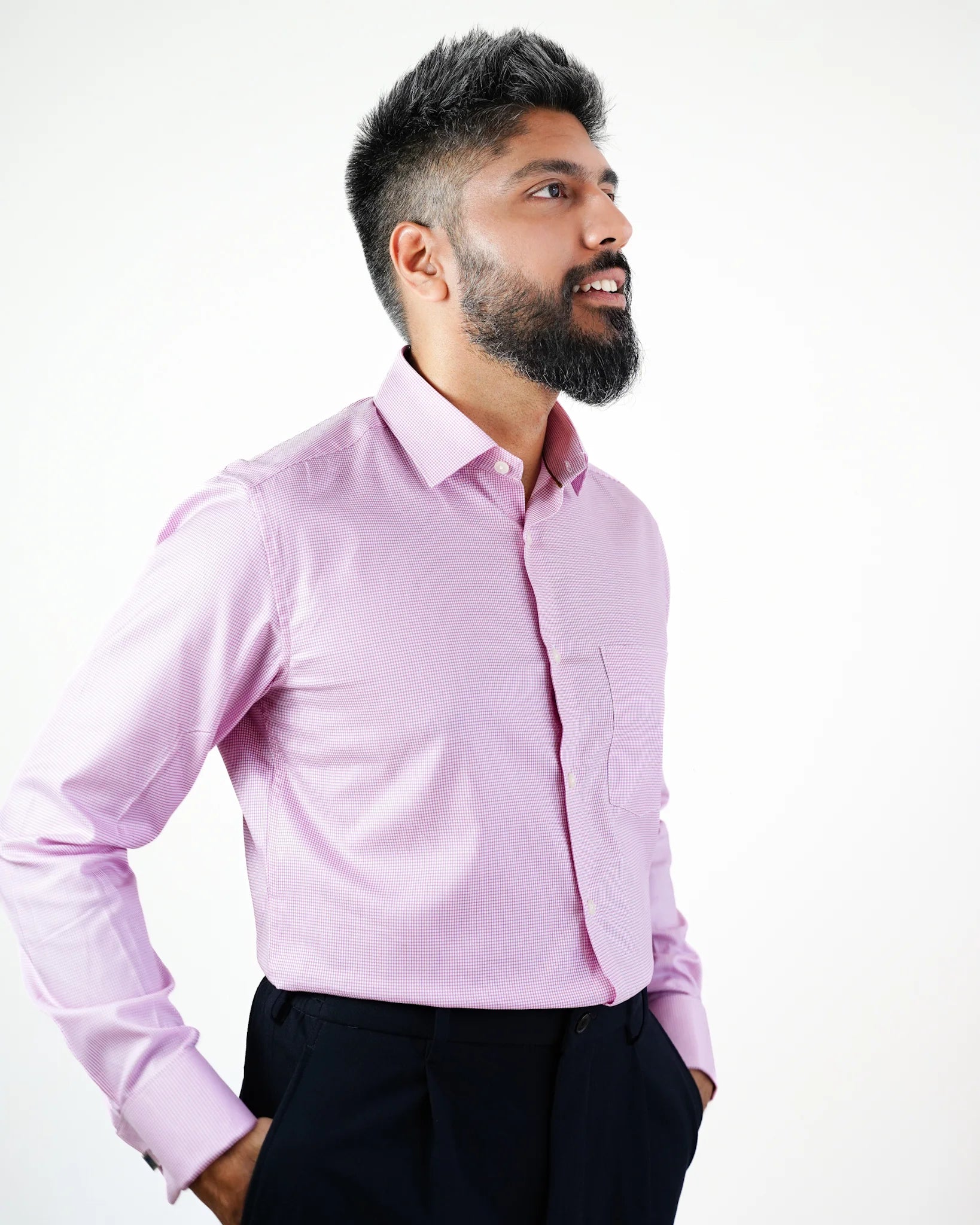 A bearded man in a pink micro check shirt against a white background.