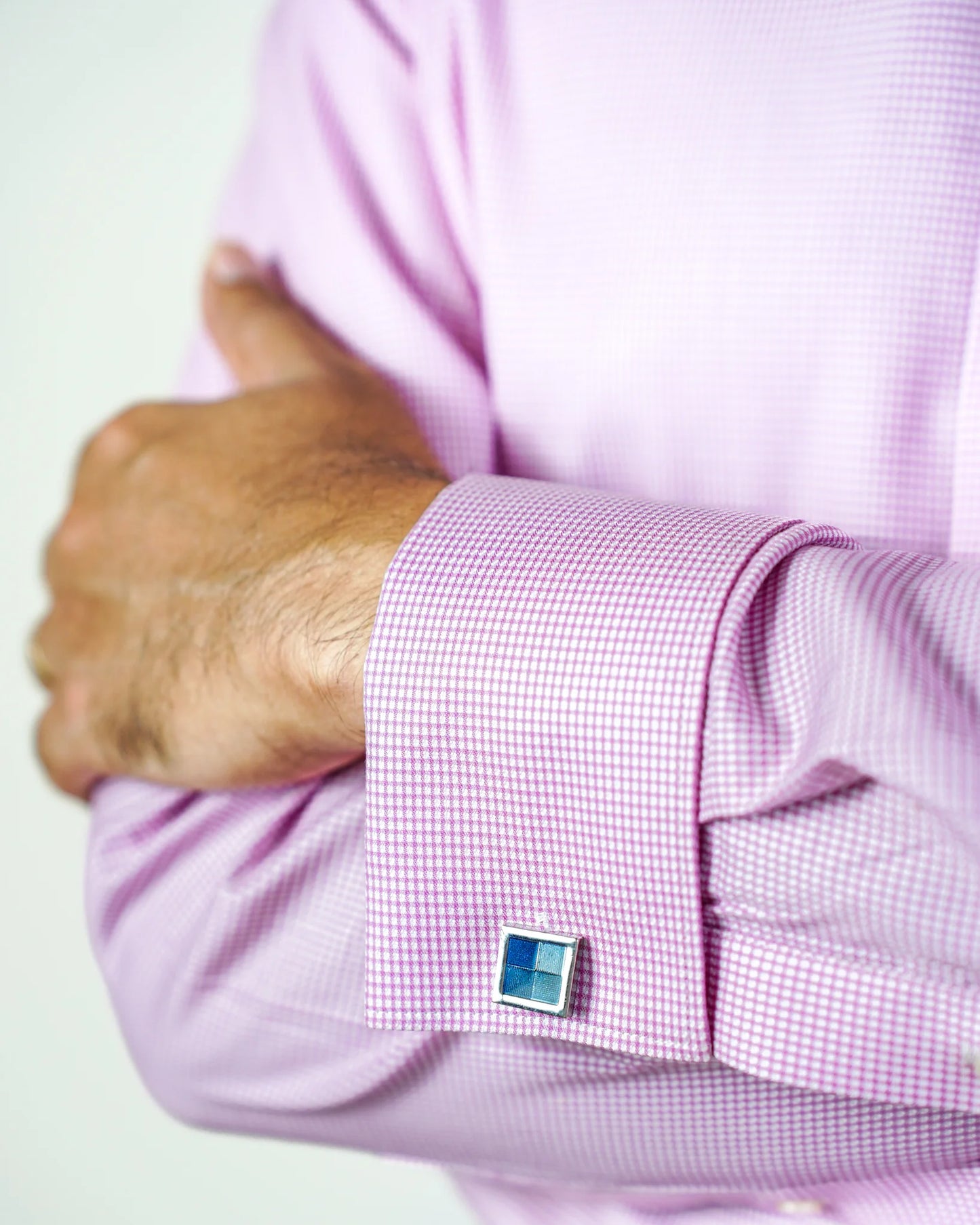 Man in pink micro check shirt with a blue cufflink.