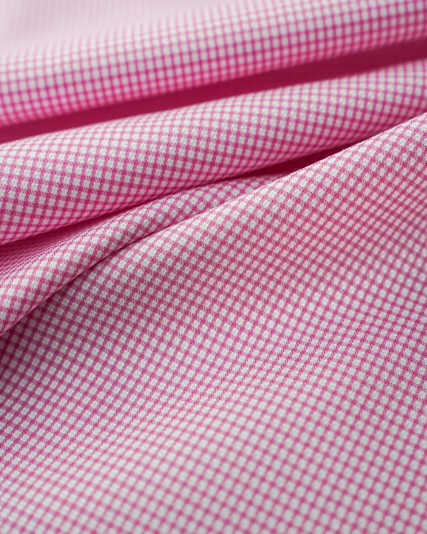 Close-up of pink gingham fabric with small white checks.