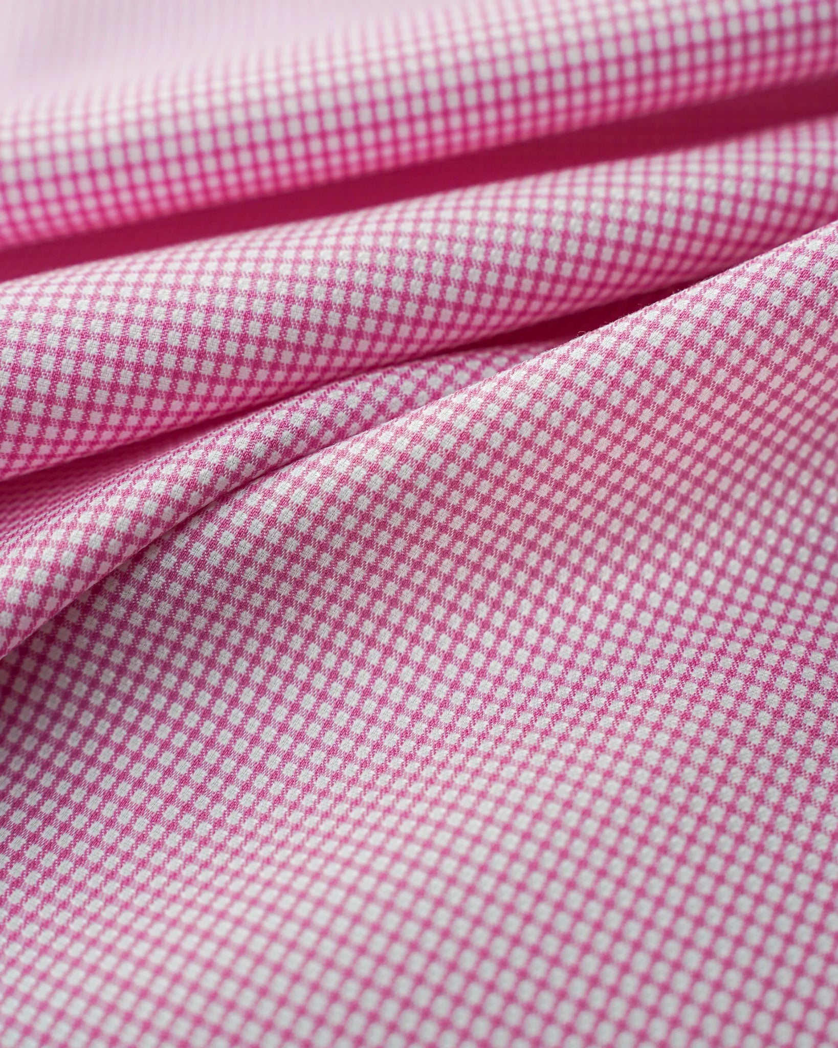 Close-up of pink gingham fabric with small white checks.