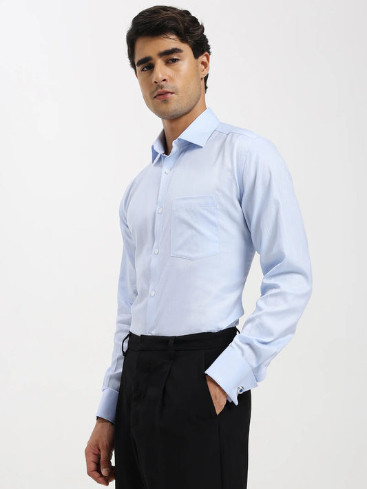 Man wearing a light blue dress shirt and black pants on a white background