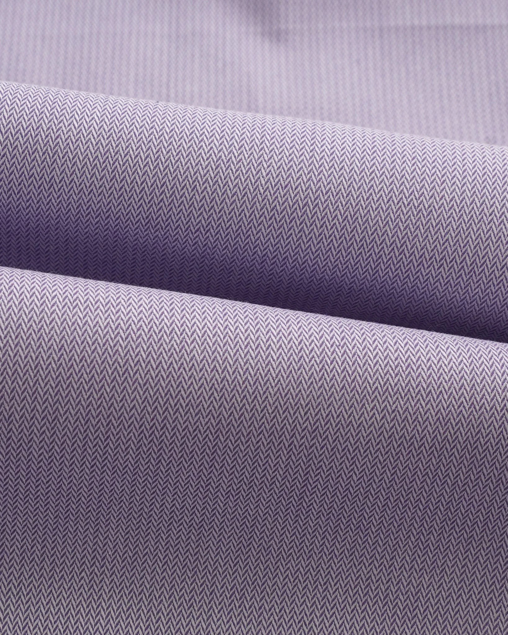 Swatch of lavender herringbone cotton fabric showing intricate weave pattern