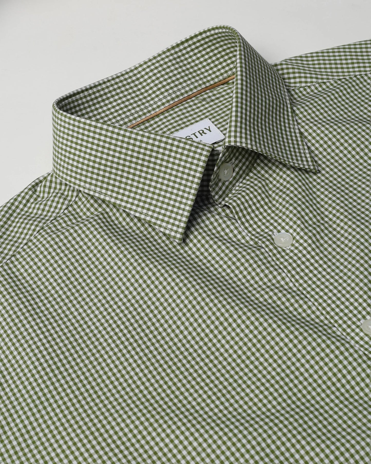 Green and white checkered shirt with a brand label on a light gray background